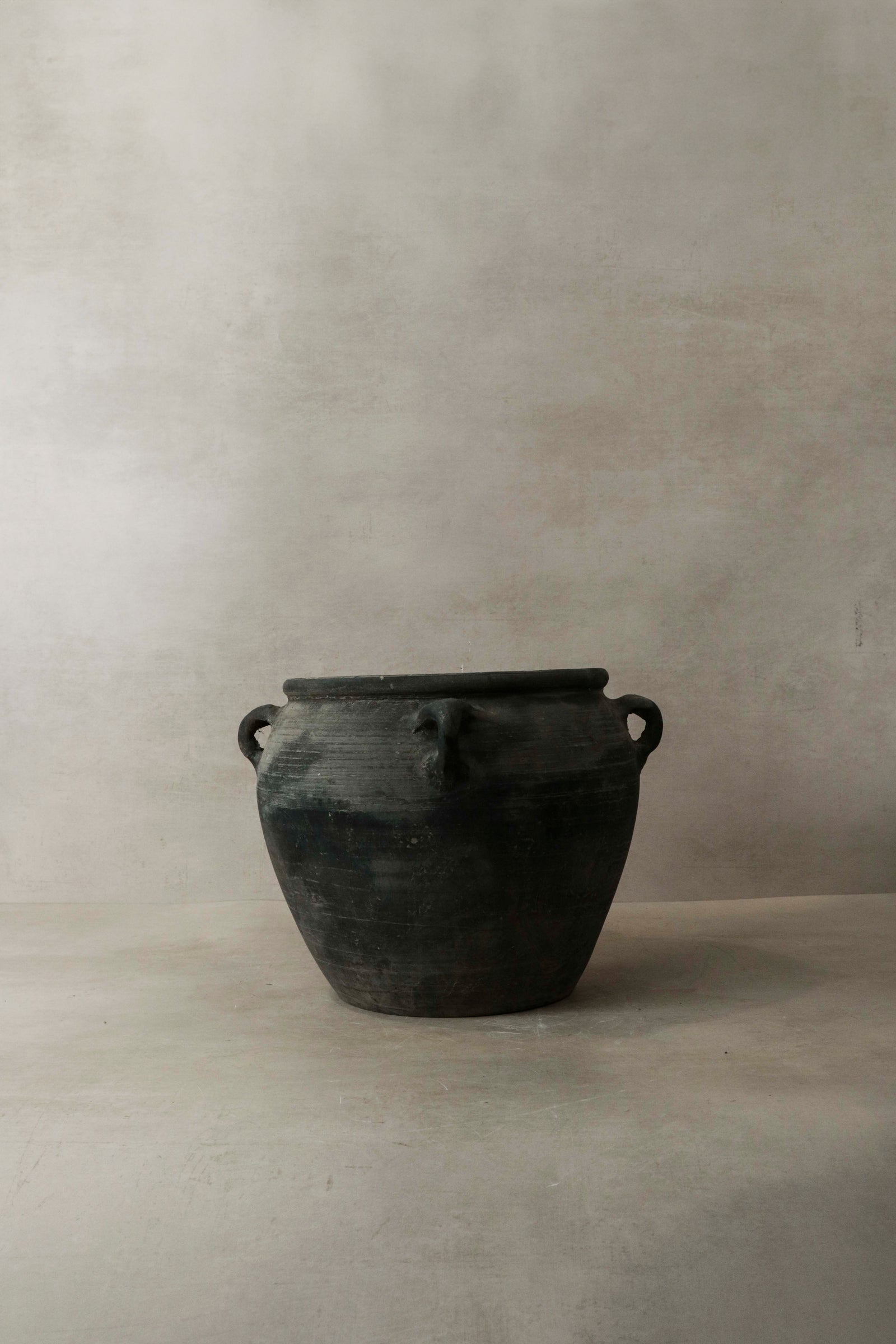 Vintage dark unglazed earthenware pot with four decorated ear handles