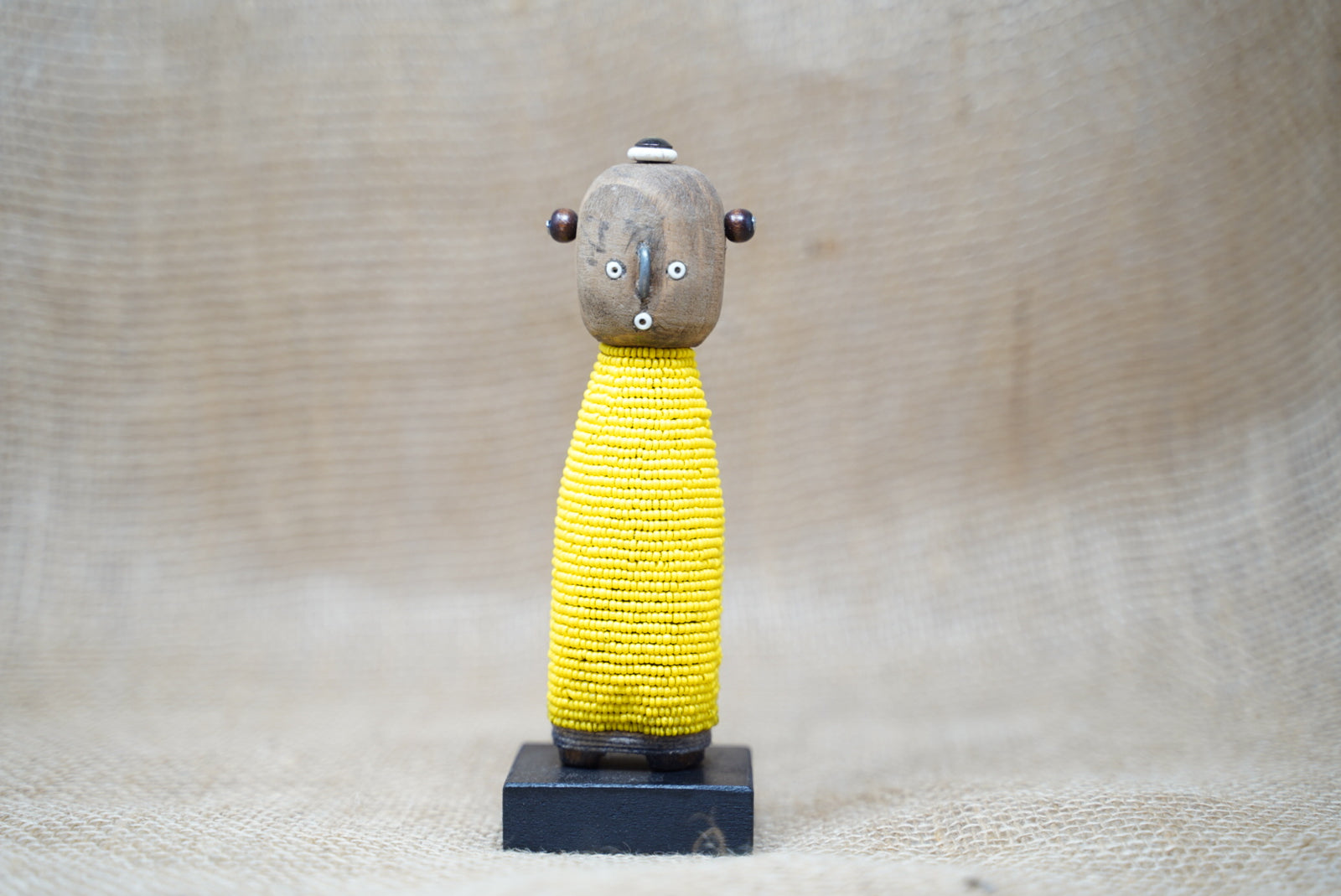 Small hand-carved yellow beaded Namji baby doll from Cameroon