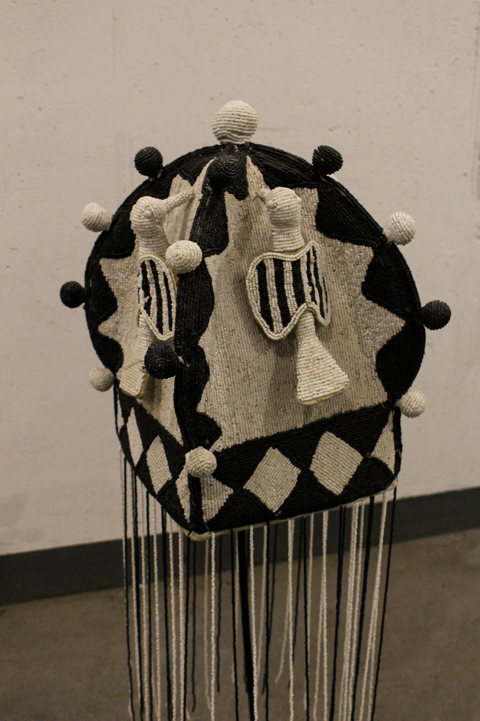 Yoruba royal beaded crown in black and white, displayed on its stand