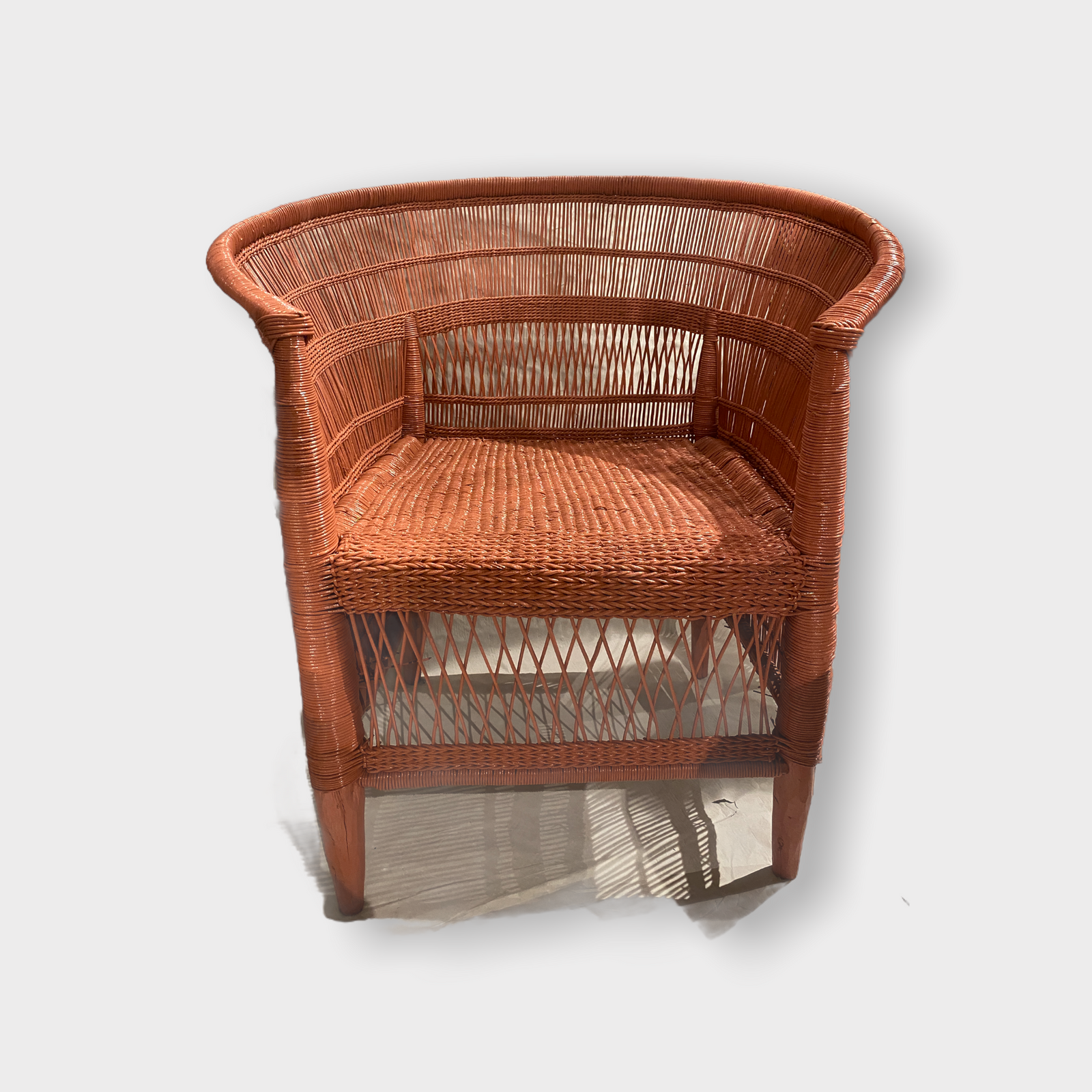 Handwoven salmon pink rattan Malawi chair with curved barrel back