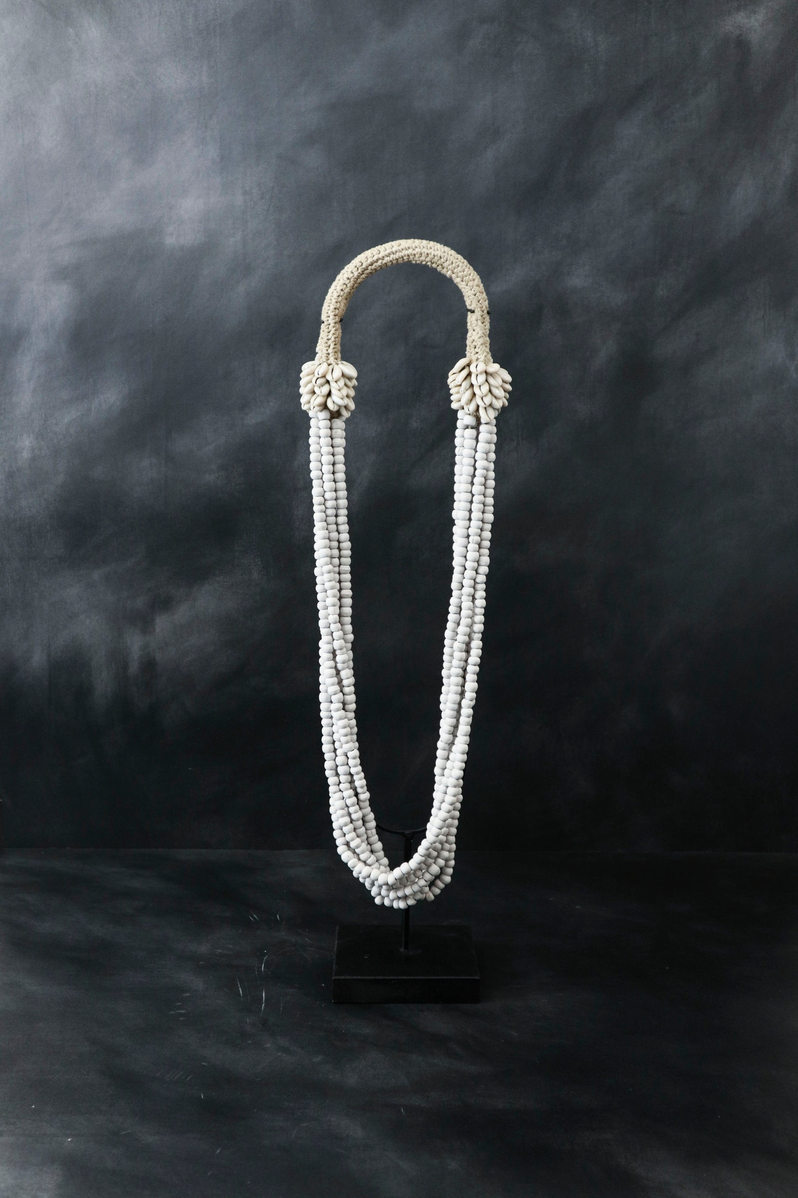 Handmade Indonesian beaded and white shell necklace on a display stand