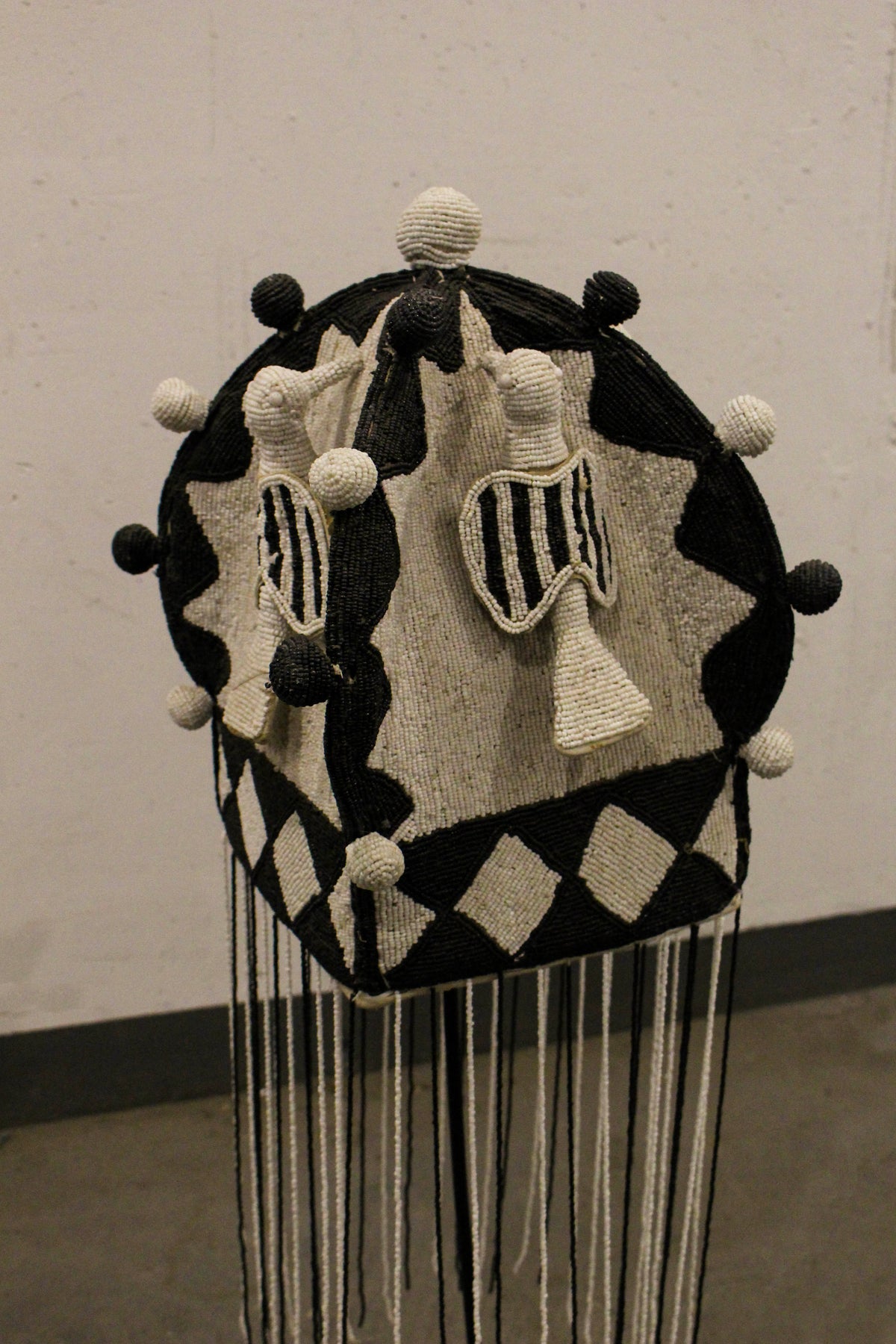 Yoruba royal beaded crown in black and white, displayed on its stand