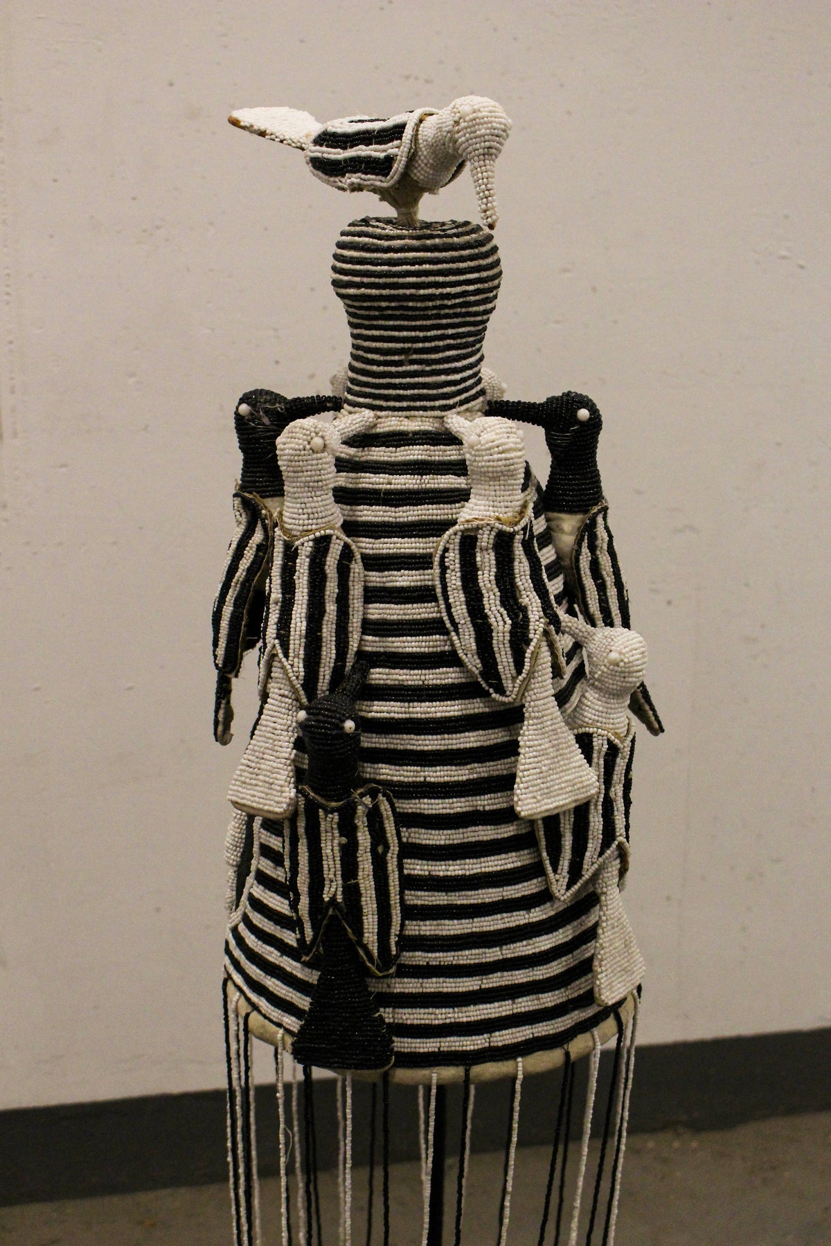 Yoruba royal beaded crown in black and white, displayed on its stand